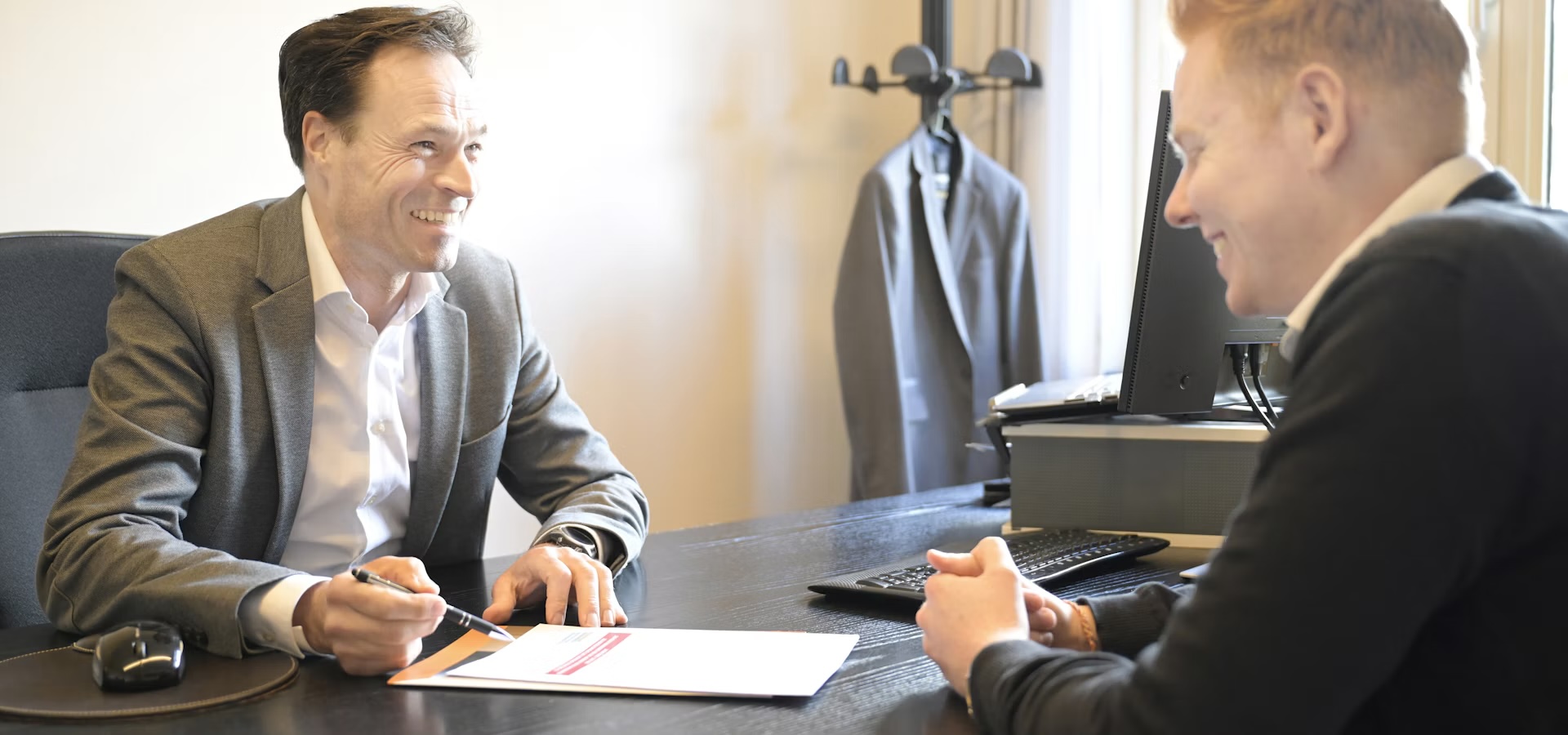 Friendly consultant smiling on the phone at a modern open-plan office desk